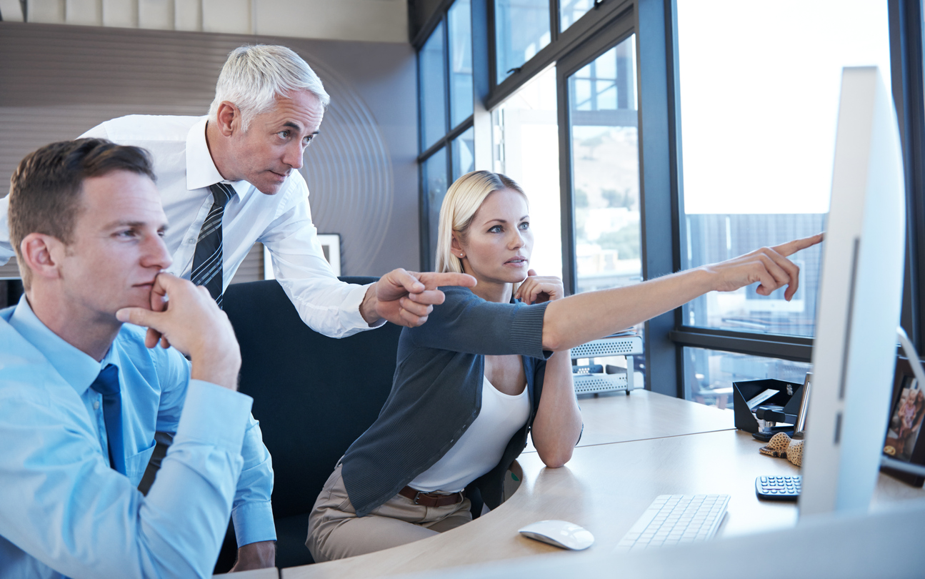 Shot of a businessman assisting two of his colleagues at a computer